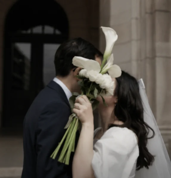 Jen and her husband on their wedding day, behind a bouquet of calla lilies